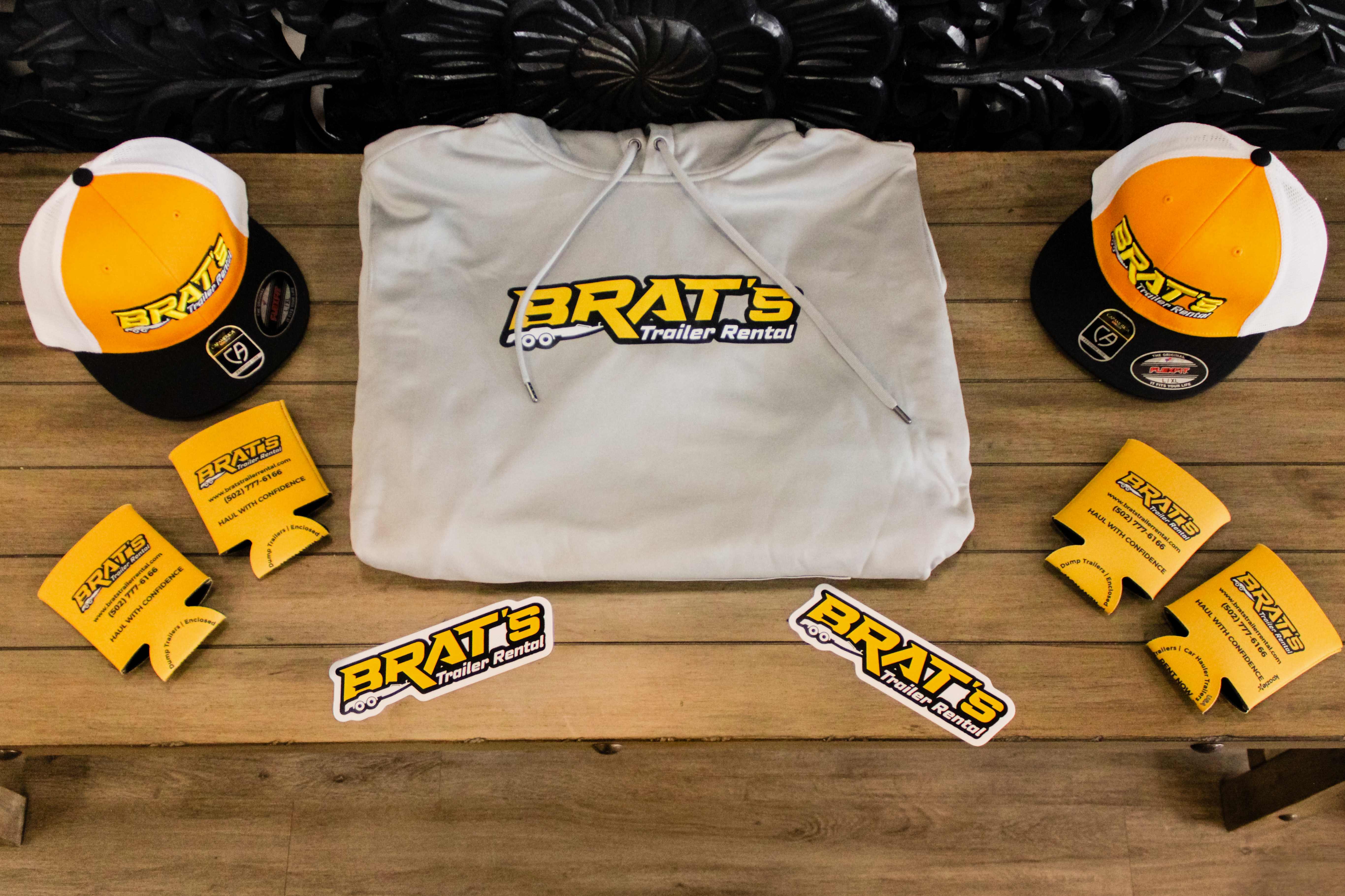 BRAT's merch flat-lay featuring hoodie, hats, koozies and stickers